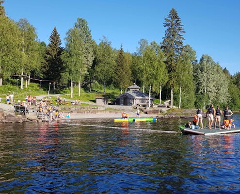 Strand ved Hurdalsjøen, mange mennesker er ute på en flåte