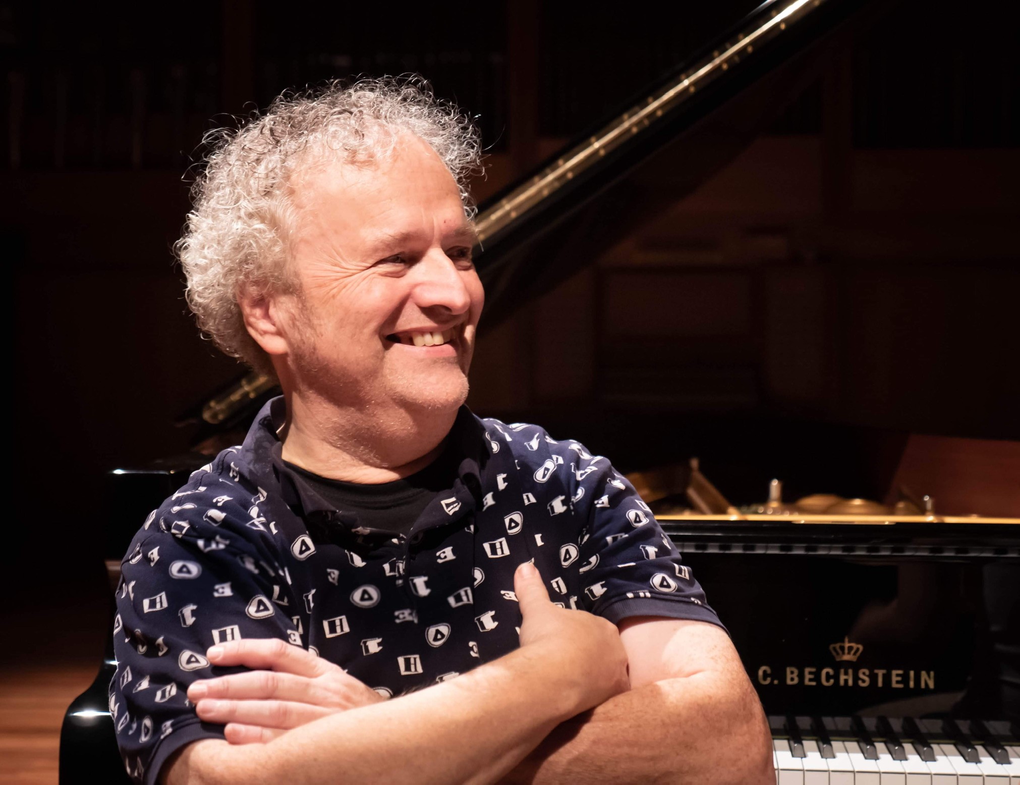 Pianisten Wolfgang Plagge sitter med armene i kors foran et flygel