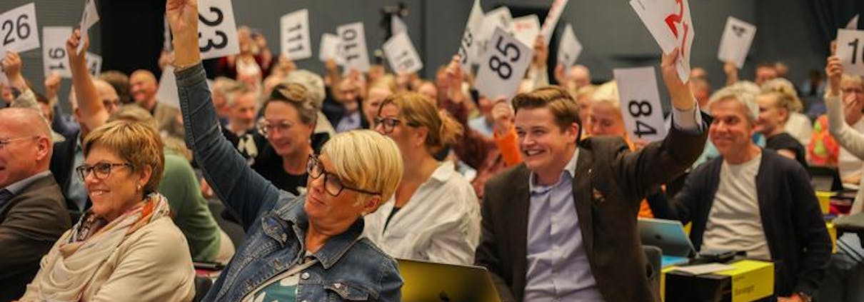 Menn og kvinner viser stemmetegn. De holder opp lapper med store tall på.