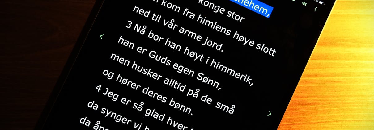 Ipad som viser teksten fra Et barn er født i Betlem i hvit skrift på sort bunn.