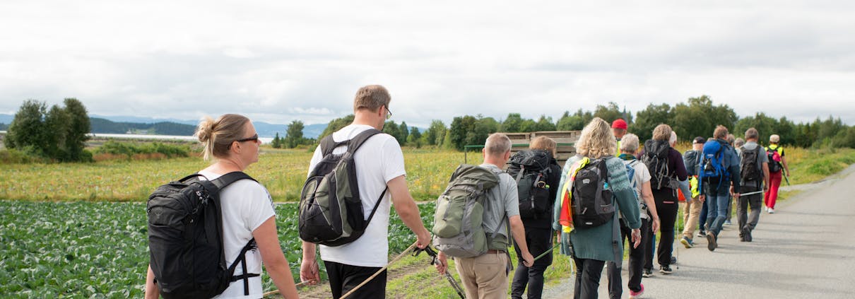 Mange mennesker går etter hverandre på en lang rekke. De holder i pinner som de bærer mellom seg.