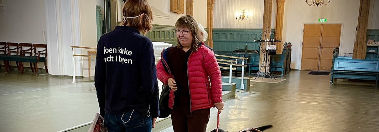 To personer snakker sammen - den ene har en førerhund. De er inne i en kirke.