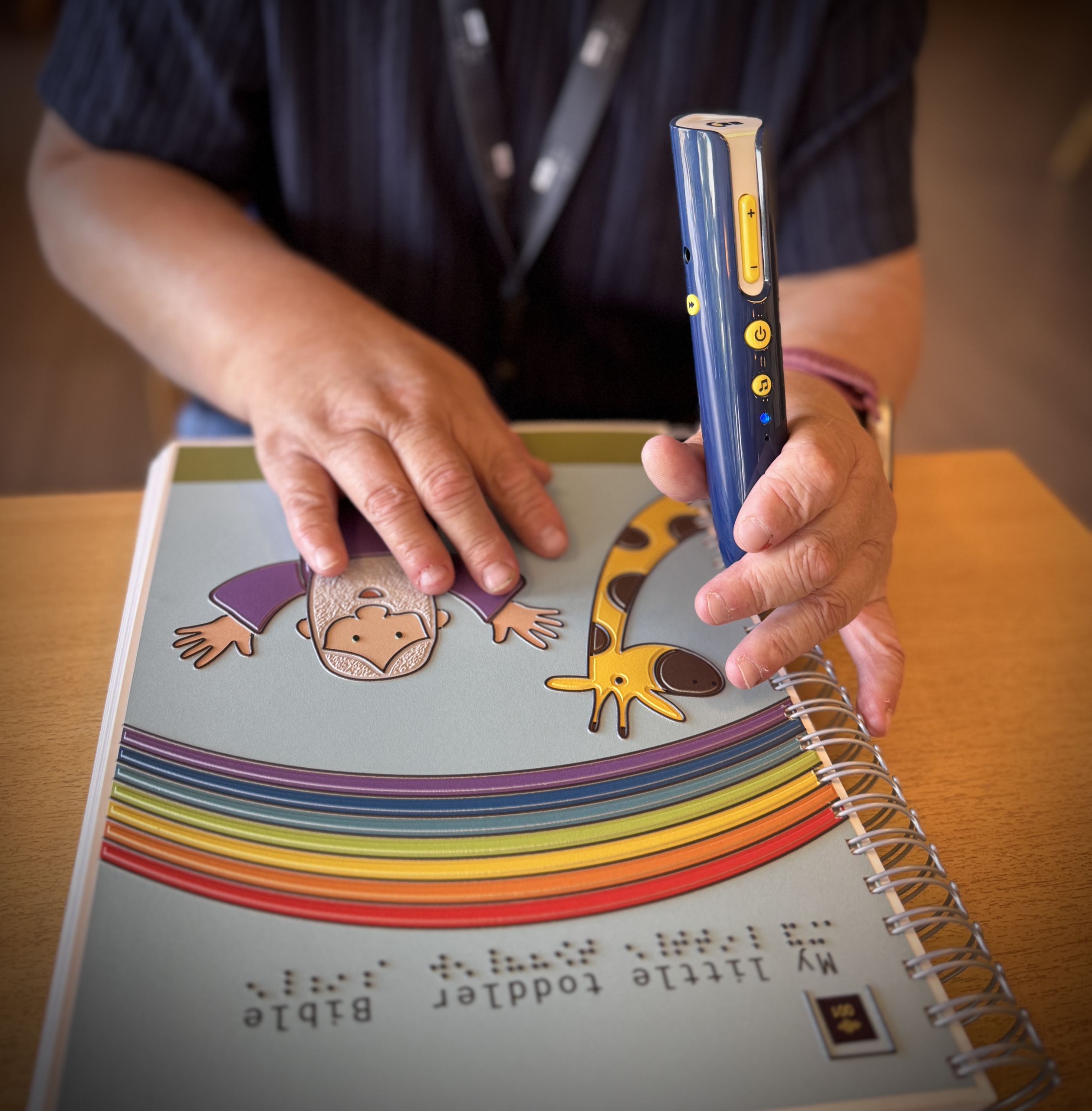 To hender kjenner på ei taktil bok og holder på en lesepenn